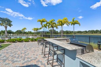 a patio with a bar and chairs and a lake in the background
